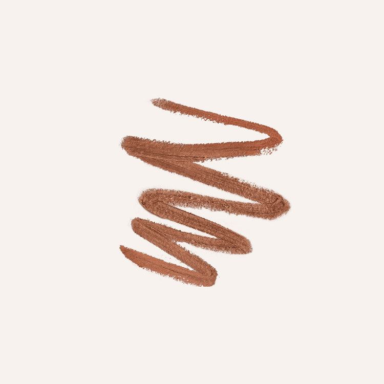 A textured swipe of auburn brown eyebrow pencil on a solid off-white background.