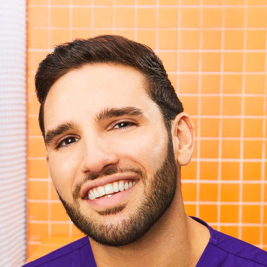 man wearing a buttoned up t-shirt holding a purple and white volleyball 