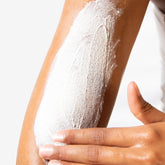 Person applying EWC Treat Get Smooth Skin Clearing Body Polish to their arm on a light background