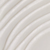 A close-up texture shot of a smooth, off-white cream or lotion with soft, curved ridges.