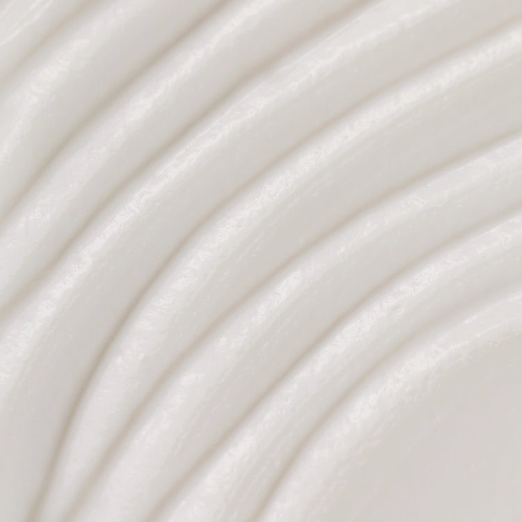 A close-up texture shot of a smooth, off-white cream or lotion with soft, curved ridges.