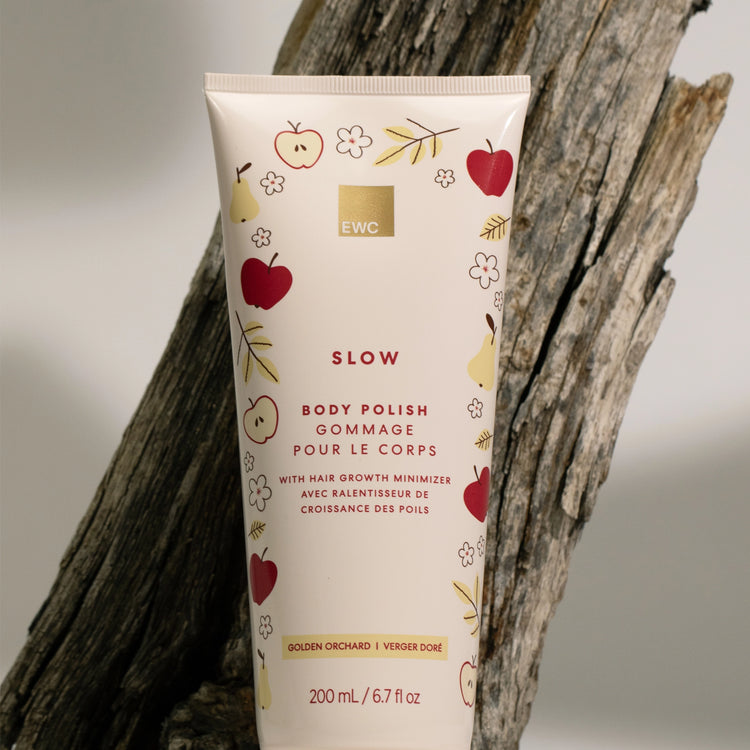 EWC Golden Orchard Body Polish against a cream background, styled against a rustic tree trunk.
