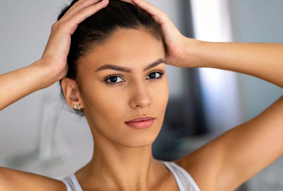 Woman adjusting her hair against a neutral background
