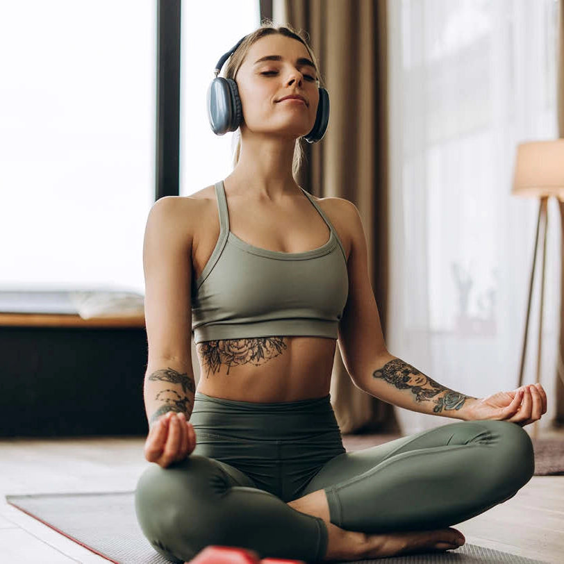 Woman meditating in a home setting with headphones on